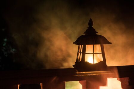 Retro style lantern at night. Beautiful colorful illuminated lamp at the balcony in the garden. Selective focusの写真素材