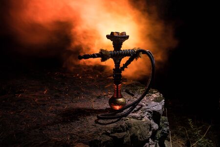 Hookah hot coals on shisha bowl with black background. Stylish oriental shisha at the forest during...