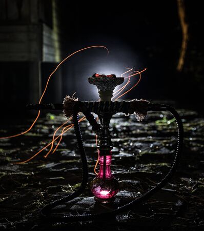 Hookah hot coals on shisha bowl with black background. Stylish oriental shisha at the forest during...