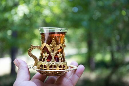 Eastern black tea in glass at the forest. Eastern tea concept. Armudu traditional cup. Green nature background. Selective focusの写真素材