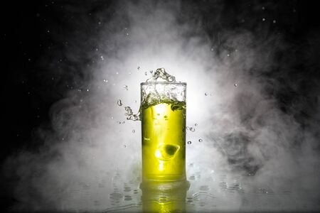 Cocktail glass splashing on dark toned smoky background or colorful cocktail in glass. Party club entertainment. Mixed light. Selective focusの写真素材