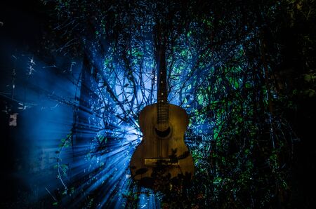 An wooden acoustic guitar at night. with spotlight for your copyspace. old broken guitarの写真素材