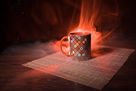 Beautiful eastern style textured ceramic cup of coffee (or tea) with smoke over dark toned background. Close up view.の写真素材