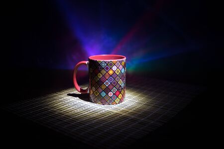 Beautiful eastern style textured ceramic cup of coffee (or tea) with smoke over dark toned background. Close up view.の写真素材