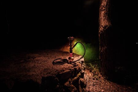 Hookah hot coals on shisha bowl with black background. Stylish oriental shisha at the forest during...