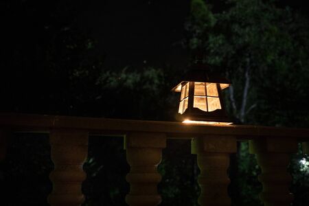 Retro style lantern at night. Beautiful colorful illuminated lamp at the balcony in the garden. Selective focusの写真素材