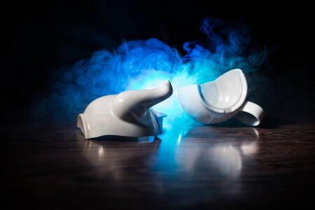 broken teapot on a dark toned foggy background. Pieces of ceramic teapot on wooden table. Selective focusの写真素材