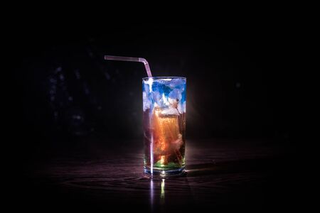 Cocktail glass splashing on dark toned smoky background or colorful cocktail in glass. Party club entertainment. Mixed light. Selective focusの写真素材