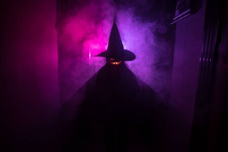 Halloween concept. Creepy silhouette in the dark corridor with pumpkin head. Toned light with fog on background.の写真素材