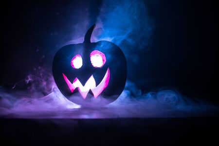 Halloween pumpkin smile and scrary eyes for party night. Close up view of scary Halloween pumpkin with eyes glowing inside at black background. Selective focusの写真素材