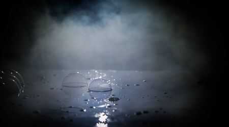 Rainbow soap bubbles on a dark background. Abstract wet surface with fog and light. Selective focus