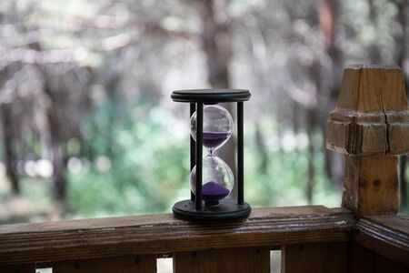 Sand running through the bulbs of an hourglass measuring the passing time in a countdown to a...