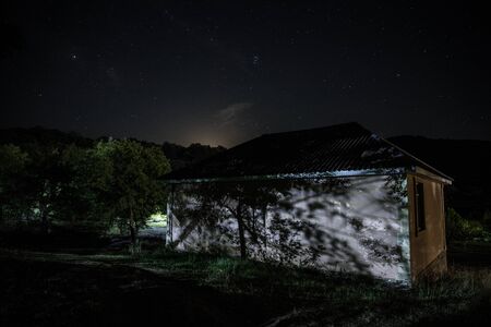Mountain night landscape of building at forest at night with moon or vintage country house at night...