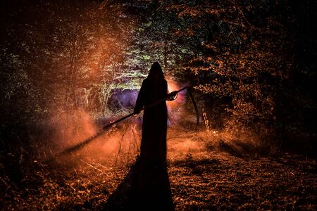 Death with a scythe in the dark misty forest. Woman horror ghost holding reaper in forest, halloween...