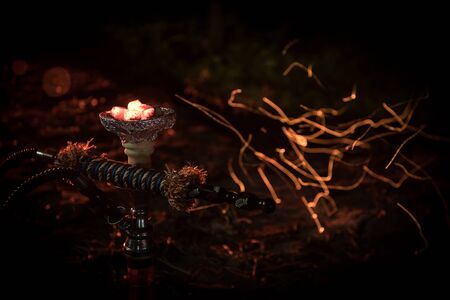 Hookah hot coals on shisha bowl with black background. Stylish oriental shisha at the forest during...