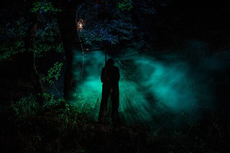 Death with a scythe in the dark misty forest. Woman horror ghost holding reaper in forest, halloween...