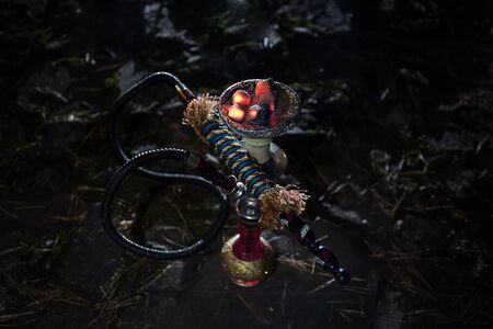 Hookah hot coals on shisha bowl with black background. Stylish oriental shisha at the forest during...