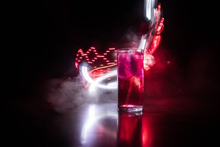Cocktail glass splashing on dark toned smoky background or colorful cocktail in glass. Party club entertainment. Mixed light. Selective focusの写真素材