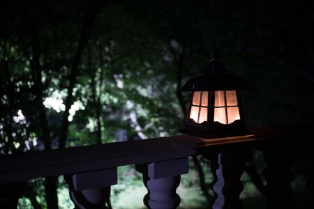 Retro style lantern at night. Beautiful colorful illuminated lamp at the balcony in the garden. Selective focusの写真素材