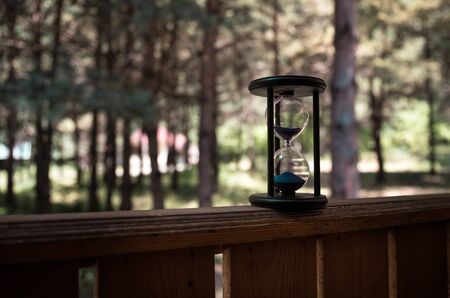 Sand running through the bulbs of an hourglass measuring the passing time in a countdown to a...