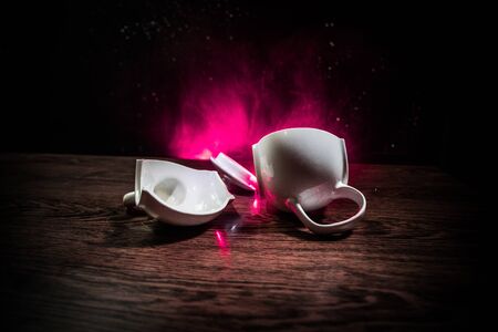 broken teapot on a dark toned foggy background. Pieces of ceramic teapot on wooden table. Selective focusの写真素材