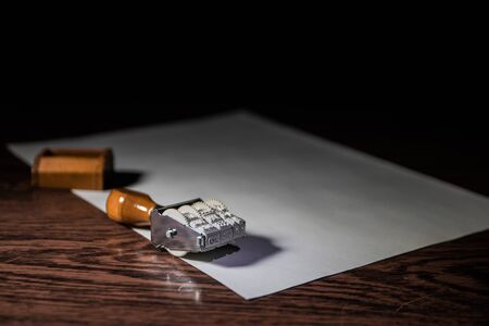 Close up view of rubber date stamper on wooden table with dark toned foggy background. Selective focusの写真素材