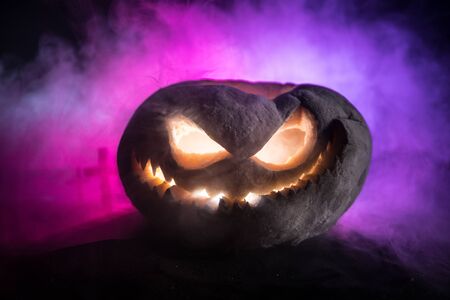 Halloween pumpkin smile and scary eyes for party night. Close up view of scary Halloween pumpkin with eyes glowing inside at black background. Selective focusの写真素材