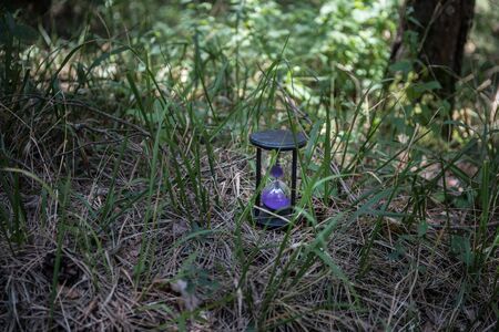 Sand running through the bulbs of an hourglass measuring the passing time in a countdown to a...