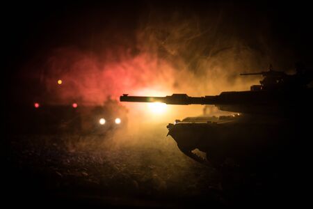 War Concept. Armored vehicle silhouette fighting scene on war foggy sky background at night. American tank ready to fight. Creative decorationの写真素材
