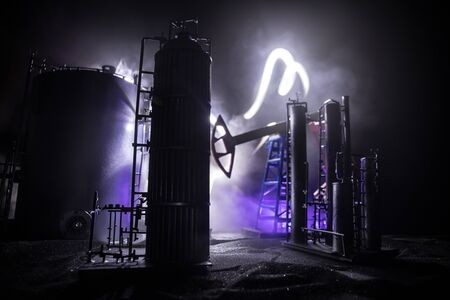 Oil pump and oil refining factory at night with fog and backlight. Energy industrial concept. Selective focus. Artwork decoration.の写真素材