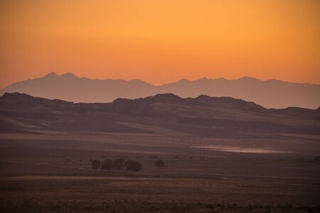 Sunset landscape view of silhouette mountains and lonely trees in Azerbaijan.の写真素材