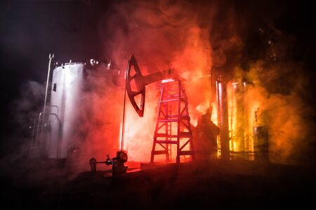 Oil pump and oil refining factory at night with fog and backlight. Energy industrial concept. Selective focus. Artwork decoration.の写真素材