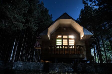 Mountain night landscape of building at forest at night with moon or vintage country house at night...