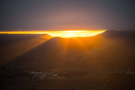 Orange sunset view at mountains in Azerbaijan. Cloudy weather. Zoom shot.