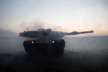 War Concept. Armored vehicle silhouette fighting scene on war fog sky background. American tank at sunset. Creative decorationの写真素材