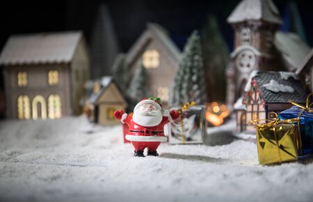 Christmas and New Year holidays concept. Little decorative cute small houses in snow at night. Traditional holiday attributes on snow. Creative artwork decorations. Empty space for your textの写真素材