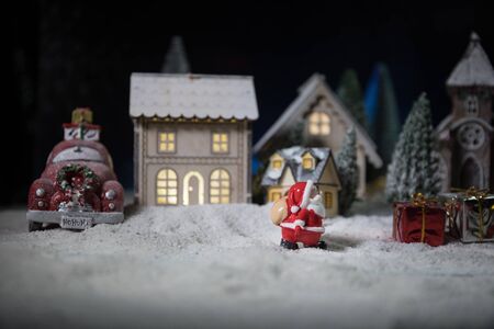 Christmas and New Year holidays concept. Little decorative cute small houses in snow at night. Traditional holiday attributes on snow. Creative artwork decorations. Empty space for your textの写真素材