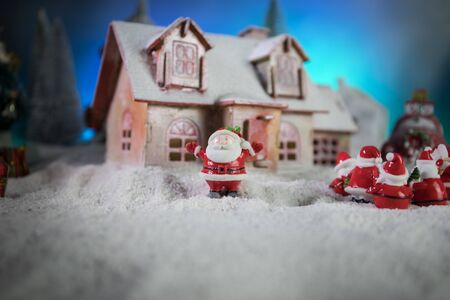 Christmas and New Year holidays concept. Little decorative cute small houses in snow at night. Traditional holiday attributes on snow. Creative artwork decorations. Empty space for your textの写真素材