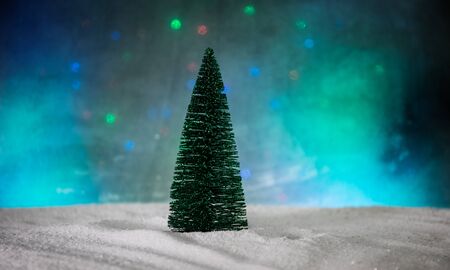Christmas decorations. Fir tree standing on snow with beautiful holiday decorated background and traditional holiday attributes. Selective focus. Empty space for your textの写真素材