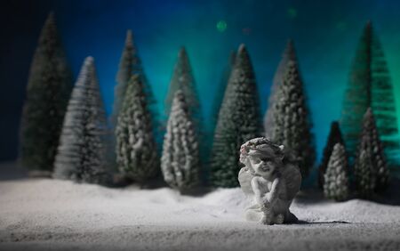Christmas angel on blur bokeh city lights at night on background. Little white guardian angel in snow. Festive background. Christmas decorations.の写真素材