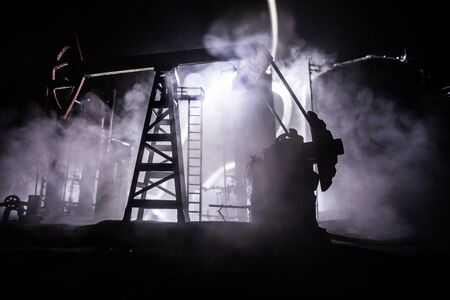 Oil pump and oil refining factory at night with fog and backlight. Energy industrial concept. Selective focus. Artwork decoration.の写真素材
