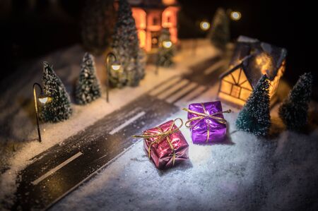 Little decorative cute small houses in snow at night in winter, Christmas and New Year miniature house in the snow at night with fir tree. Holiday concept. Selective focusの写真素材