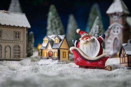 Christmas and New Year holidays concept. Little decorative cute small houses in snow at night. Traditional holiday attributes on snow. Creative artwork decorations. Empty space for your textの写真素材