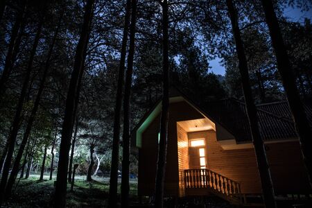 Mountain night landscape of building at forest at night with moon or vintage country house at night...
