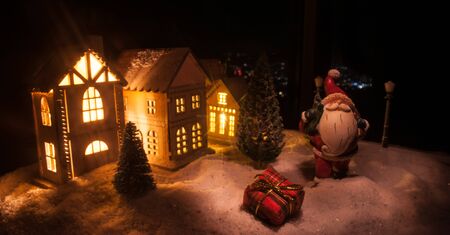 Little decorative cute small houses in snow at night in winter, Christmas and New Year miniature...