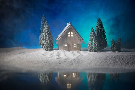 Christmas and New Year holidays concept. Little decorative cute small houses in snow at night. Traditional holiday attributes on snow. Creative artwork decorations. Empty space for your textの写真素材