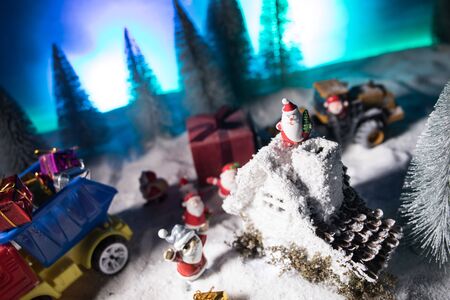 Christmas and New Year holidays concept. Little decorative cute small houses in snow at night. Traditional holiday attributes on snow. Creative artwork decorations. Empty space for your textの写真素材