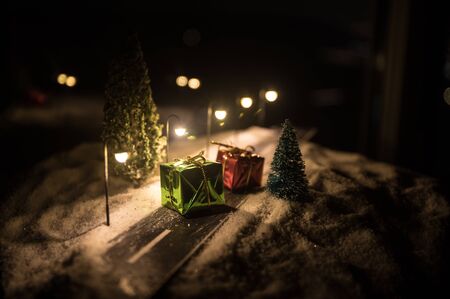 Little decorative cute small houses in snow at night in winter, Christmas and New Year miniature house in the snow at night with fir tree. Holiday concept. Selective focusの写真素材