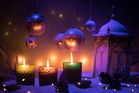 Christmas decoration with burning candles on a dark background. Christmas ornaments over dark golden background with lights. Creative artwork decoration.の写真素材