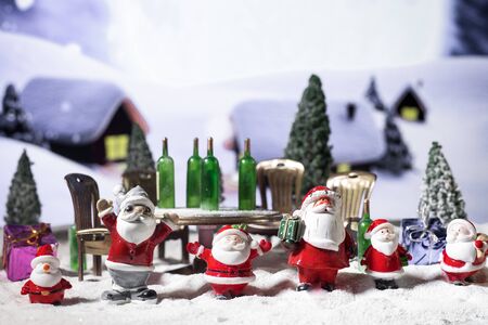 Funny Christmas concept. Creative artwork decoration. Alcoholic Santa Drinking a Wine Bottle on snow. Drunk santas have a party. Selective focus.の写真素材